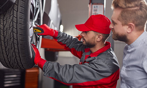 Mechanic Examining BMW Tire With Client